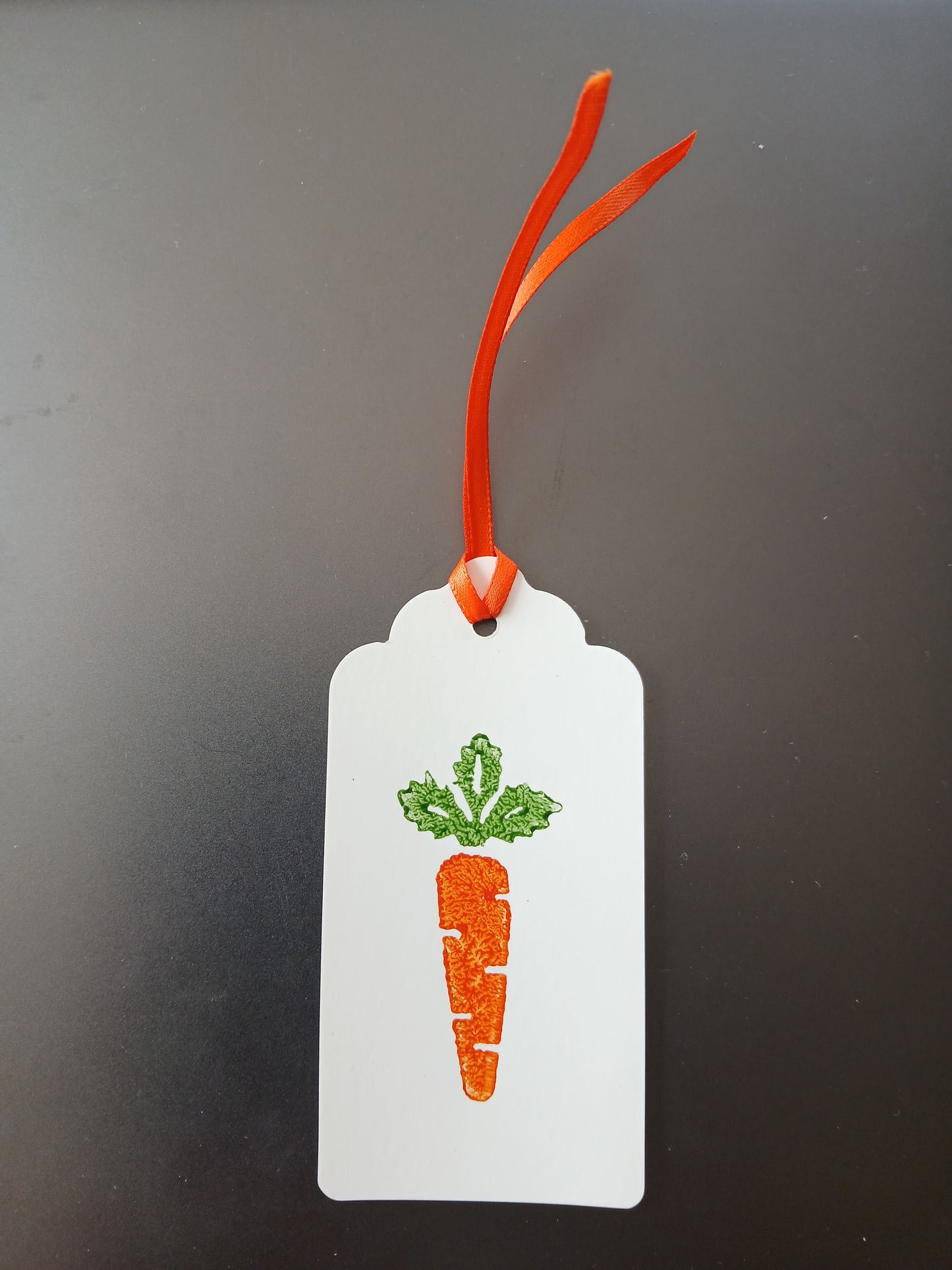 Carrot in Orange & Green on oblong white gift tag with ribbon
