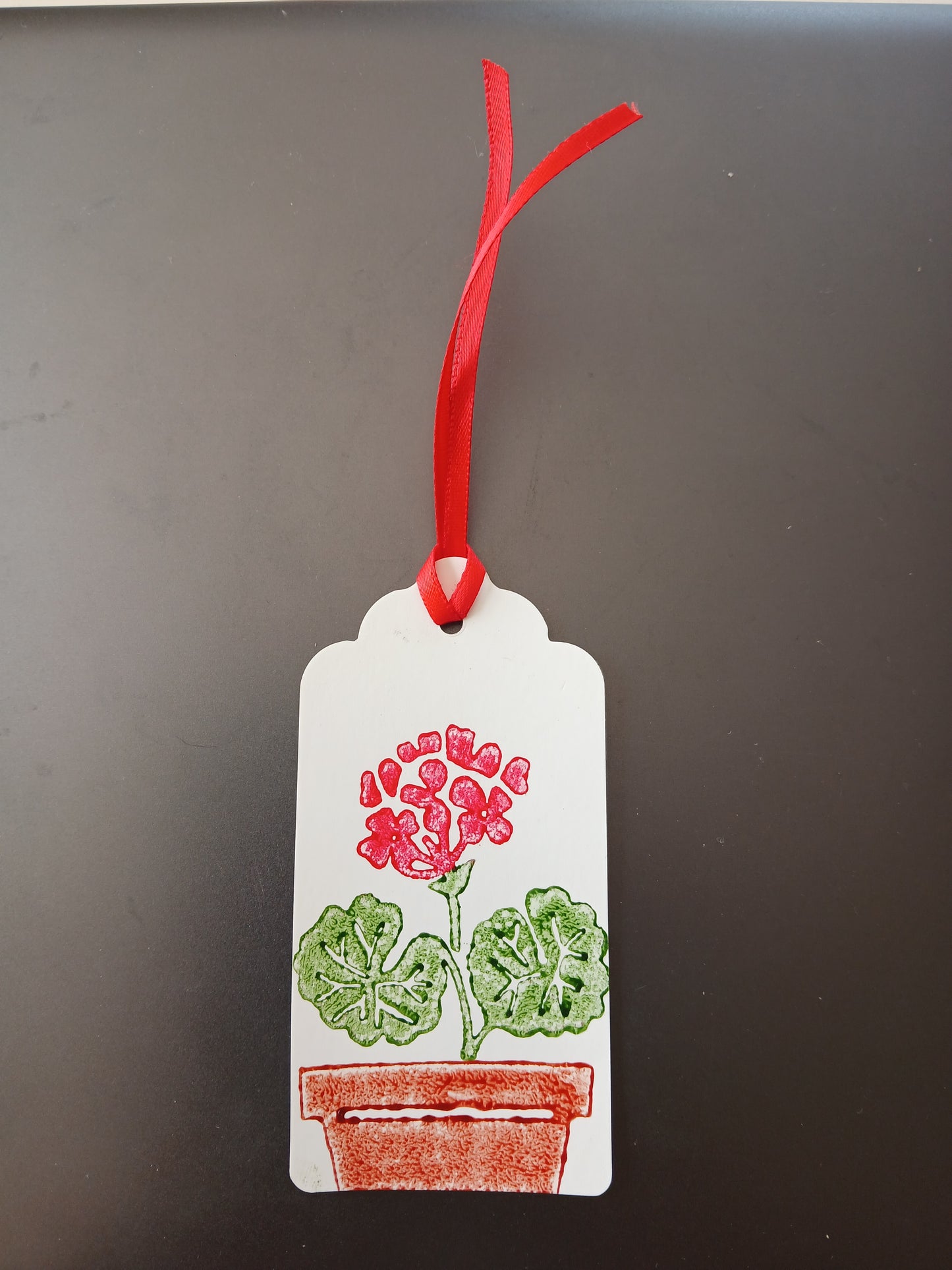 Geranium in Red, Green & Brown on oblong white gift tag with ribbon