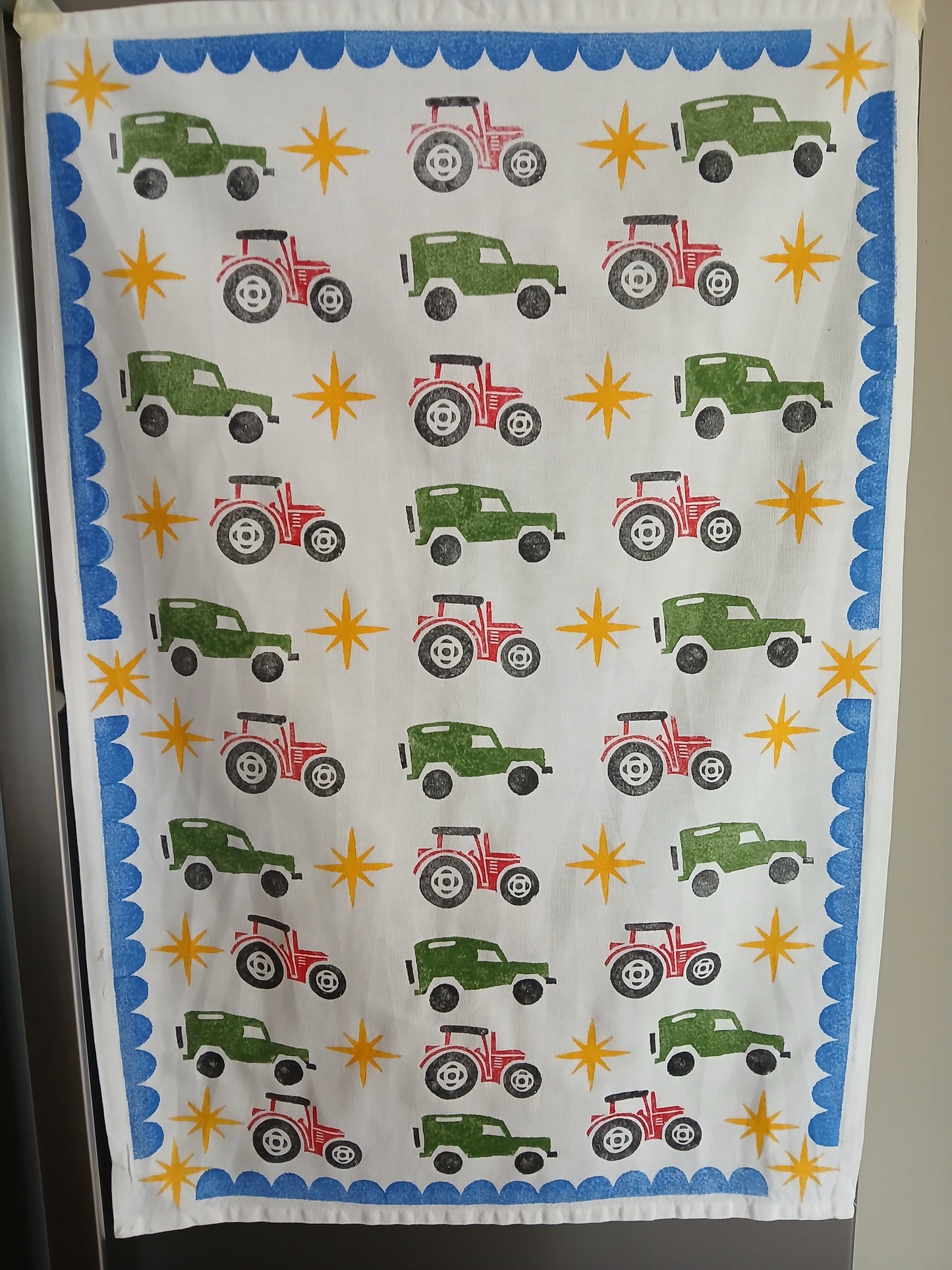 Tractors & Landrovers with scalloped & stars in red, green, black, blue & mustard on cotton teatowel